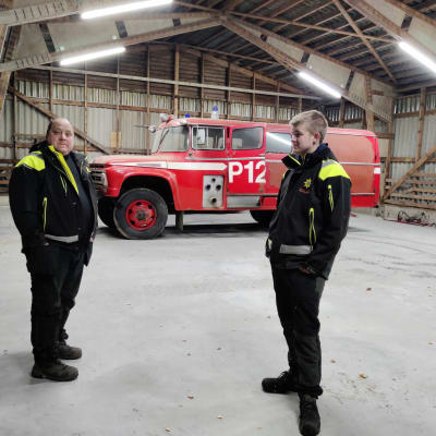 Två män står i en hall där det finns en rktigt gammal brandbil. De heter Kimmo Wiman och Emil Nyman.