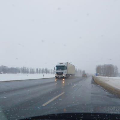 Lastbil kör i dåligt före i snöslaskväder.