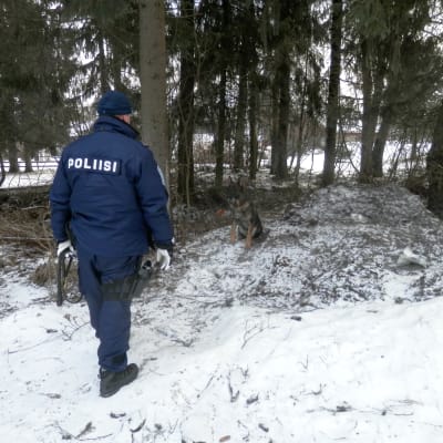 Polisen undersöker terrängen runt mordplatsen på Getbrovägen i Jakobstad med schäferhund