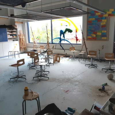 Ett klassrum med stolar huller om buller och sprayad färg på fönstret.
