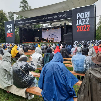 Yleisöä sadetakeissa Porin jazzfestivaalien katsomossa.