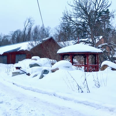 En snöig väg, stenhögar täckta av snö, gamla röda byggnader, en röd paviljong.