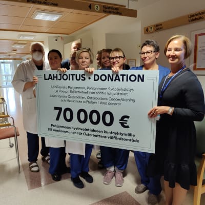 Flera personer står och håller i en stor check på 70 000 euro.