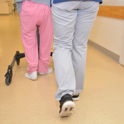 En fysioterapeut hjälper en äldre att gå.
