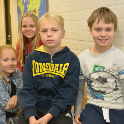 Elever i Sjundeå svenska skola sitter på bord och stolar. Här syns Leia Seppä (längst bak), Wilma Holmberg, Walter Forsén och Robert Siro.