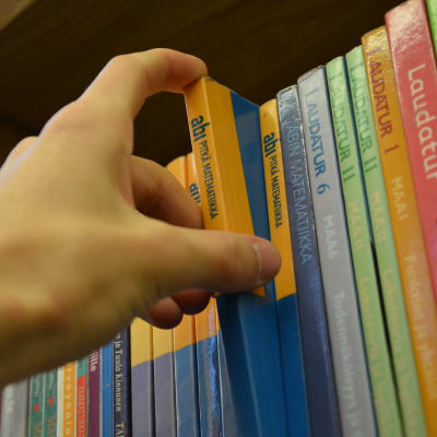 Bild på en hand som rör vid gymnasieböcker