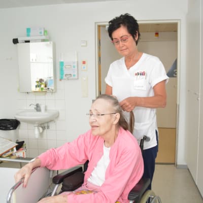 Susanne Enholm kammar Gullevi Silfvast hår på bädden i Hangö.