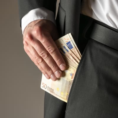 man som sätter femtioeurosedlar i sin ficka.