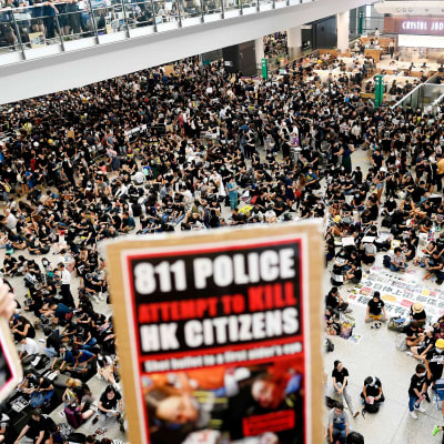 Demonstranter samlades på Hongkongs internationella flygplats på måndagen. En del bar på skyltar där polisen beskylls för att försöka döda medborgare i Hongkong.
