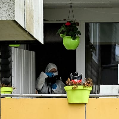 Suojavarusteissa oleva rikospaikkatutkija parvekkeella.