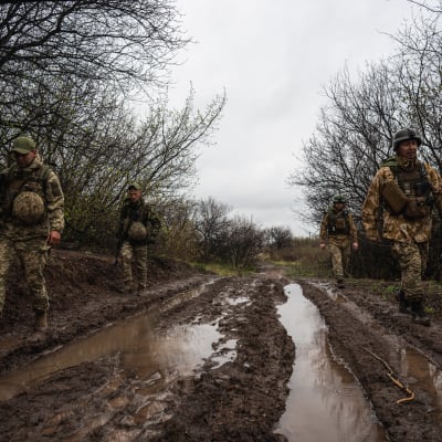 Ukrainalaisia sotilaita kävelee mutaisella tiellä.