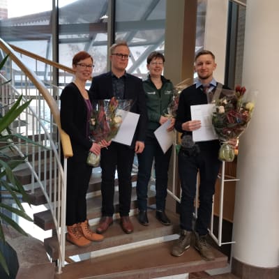 Neljä kukitettua henkilöä seisoo portaissa. 