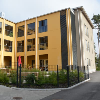 Ett gult hus på en innegård som är Villa Anemone, ett äldreserviceboende i Karis.