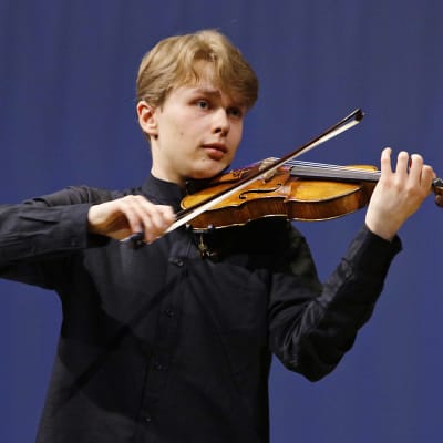 Viulisti Otto Antikainen soittamassa viulua kasvoillaan kaihoisa ilme.