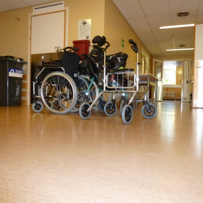 Rullstol och rollator i en sjukhuskorridor.