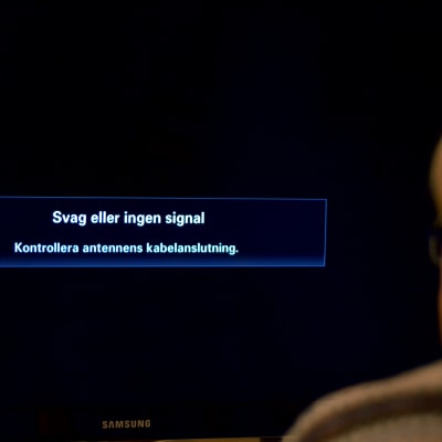 En man tittar på en tv där det på skärmen står "Svag eller ingen signal".