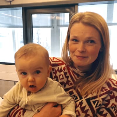 Porträttfoto av Linn Holmgård med bebis i famn.