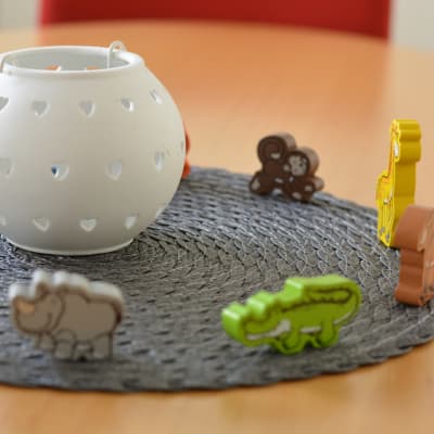 Leksaksfigurer  som föreställer djur står på ett bord, runt en vit, rund lykta