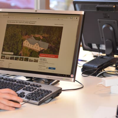 Datorskärm där det pågår nätauktion på ett stort ljusgult trähus.