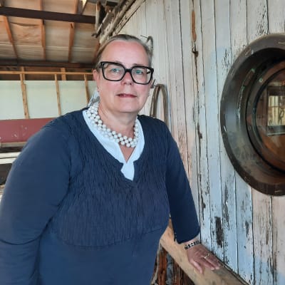 En kvinna med mörka kläder står intill kajutan på ett gammalt fartyg