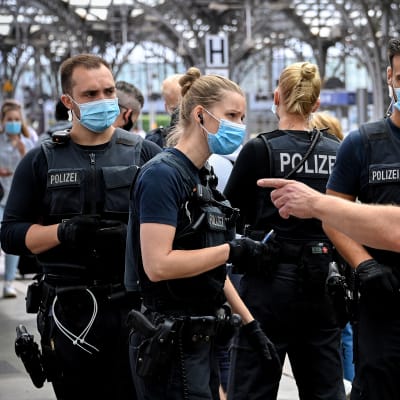 Poliser stoppar en person i Köln som brutit mot coronareglerna.
