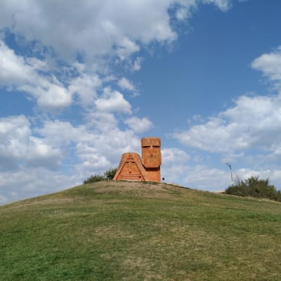 En skulptur föreställande en stiliserad man och kvinna uppe på en kulle.