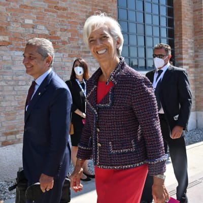 Europeiska centralbankens chef Christine Lagarde ler, omgiven av män i kostym.