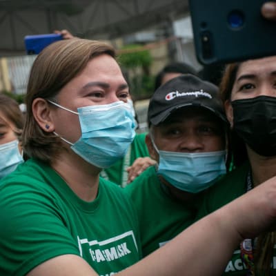 Sara Duterte iklädd munskydd omgiven av människor