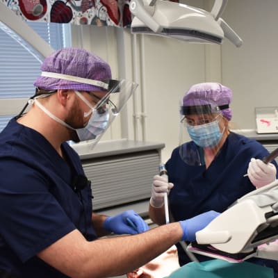 Tandläkare och tandskötare undersöker en patient.