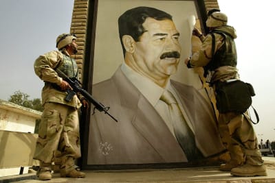Yhdysvaltalaiset sotilaat repivät Saddam Husseinin henkilökuvaa irti seinästä.
