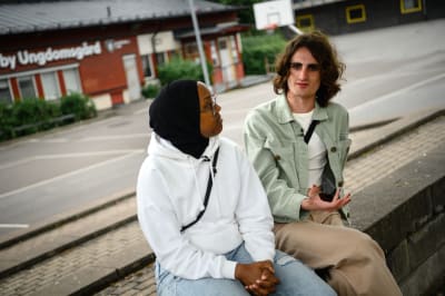 Ellie Ala-Kojola och Sheyma Isse sitter på en bänk och pratar.
