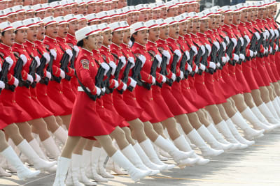 Kvinnor i den kinesiska armén marscherar. De har röda kjolar och vita stövlar.