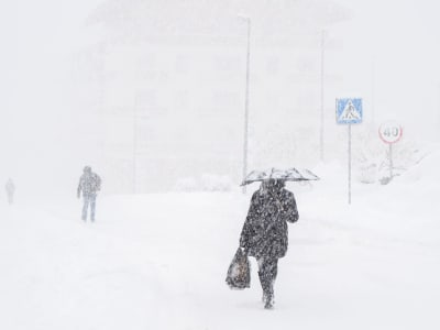 Människor går på en gata medan det snöar.