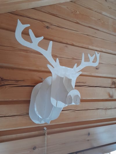 Ett älghuvyd gjord av trä hänger på en vägg.