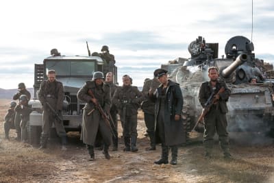 Ett större gäng beväpnade nazister poserar framför en pansarvagn och en lastbil.