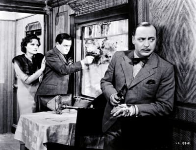 Kaksi miestä ja nainen ovat linnoittautuneina junan ravintolavaunuun: toinen miehistä nojailee seinään ase kädessä, toinen tähtää pistoolilla rikkinäisestä ikkunasta ulos, nainen seisoo hänen takanaan.