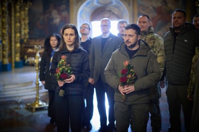 Sanna Marin och Volodymyr Zelenskyj inne i en kyrka. De håller i blombuketter.