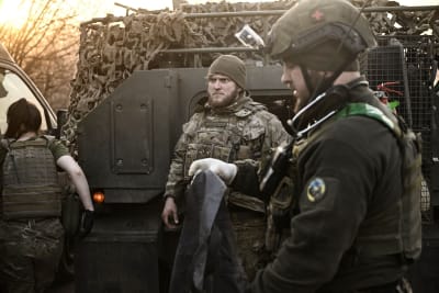 Kevyesti haavoittuneita ukrainalaissotilaita seisoo tankin edessä.