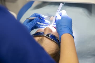 En tandläkare undersöker och mäter tänderna på ett barn.