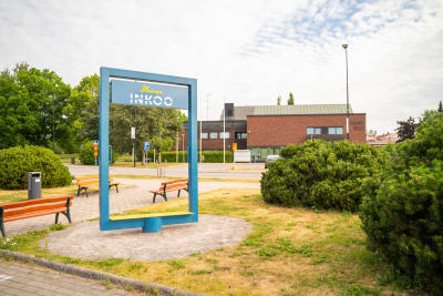 Ingå kyrkby sommaren 2023 med kommungården i bakgrunden och en skylt som föreställer en blå ram, "Iloinen Inkoo".