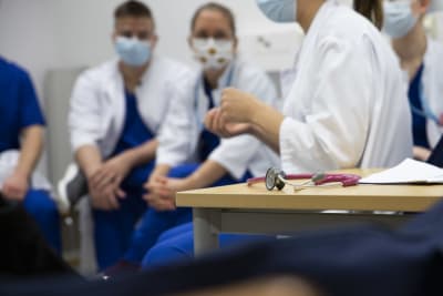 Stetoskop på ett bord på ett sjukhus. I bakgrunden hälsovårdsstuderande. 