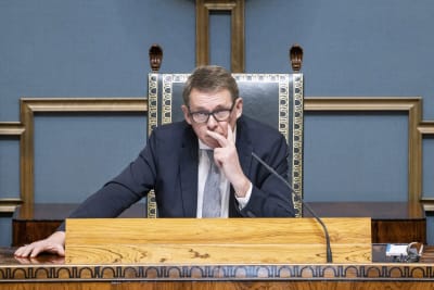 Matti Vanhanen i pampig talmansstol i riksdagen, med handen mot kinden.