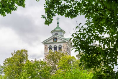 En kyrka syns mellan trädgrenar.