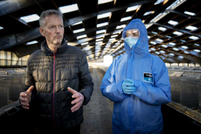 Mette Frederiksen i skyddsutrustning bredvid Peter Hindbo i en pälsfarm.