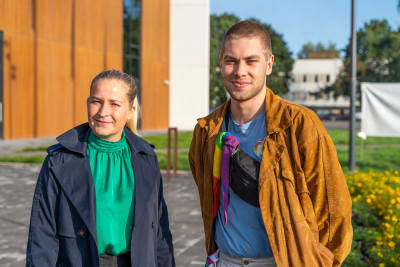 En kvinna och man framför ett hus med rostfärgad fasad.