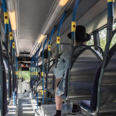 En person med hatt inne i en buss från Esbo till Helsingfors.