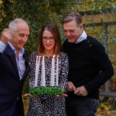 Luciajuryn med Stefan Lundberg, Anna Bäck och Riko Eklundh tänder en luciakrona med levande ljus.