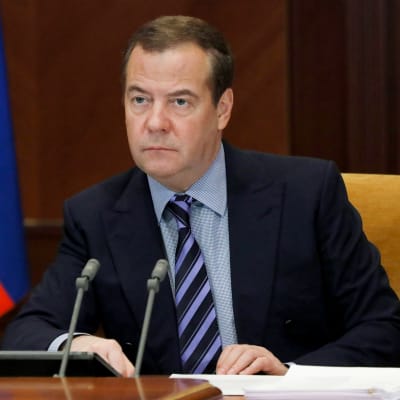 Rysslands förre president Dmitrij Medvedev sitter bakom ett bord, bredvid en rysk flagga.