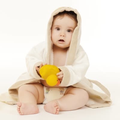 En babys i badkappa med en gul badanka i handen.