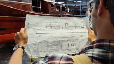 Klassikkoveneiden asiantuntija Jani Vahto tarkastelee salonkivene Boniton piirustuksia verstaalla